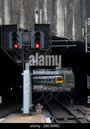 West Midlands Railway classe 323 323243 arrivant à Birmingham New Street avec un train en croix qui passe un signal ferroviaire rouge Banque D'Images