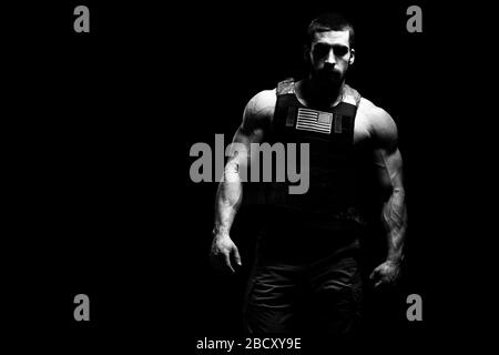 Bodybuilder Portrait de soldat avec maillot de corps sans manches et drapeau US sur un fond noir Banque D'Images