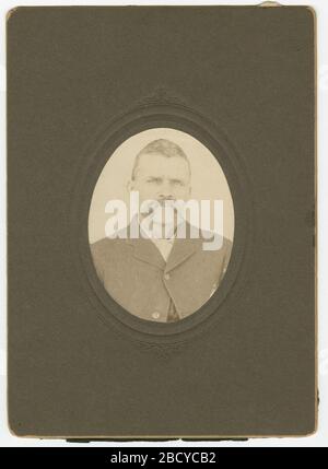 Photographie d'un homme avec une moustache portant une veste sombre. Portrait d'un homme portant une veste de couleur sombre et une chemise légère sur une carte d'armoire noir et blanc. Le bouton supérieur de la veste est boutonné et il a une moustache. La photo ovale est sur le cartstock noir. Il n'y a pas d'inscriptions à l'avant ou à l'arrière. 2014.61.13 Banque D'Images