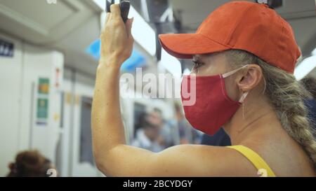 Une femme voyage une balade caucasienne à l'airtrain en train terrestre avec un masque médical de protection. Fille touristique à airtrain avec respirateur. Masque de personnes. Banque D'Images