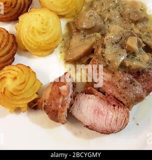 filet de porc dans la croûte de bacon avec champignons sautés et pommes de terre duchesse Banque D'Images