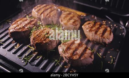 Délicieux bifteck de viande juteuse sur le gril. Faire cuire au bœuf à la sauce au roaster électrique, au romarin, au poivre noir et au sel. Ralenti. Banque D'Images