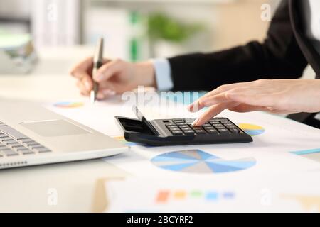 Gros plan sur les mains de la femme exécutive calculer avec calculatrice et graphiques sur un bureau au bureau Banque D'Images