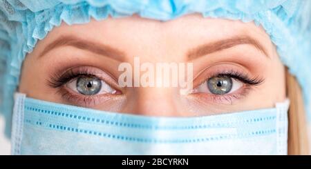 Gros plan sur l'œil du médecin chirurgien féminin adulte portant un masque de protection et un capuchon. Santé, service médical d'urgence et concept de chirurgie