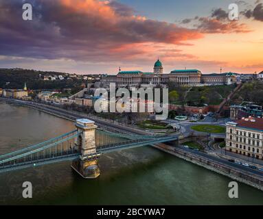 Budapest, Hongrie - vue aérienne du pont de chaîne Szechenyi totalement vide avec la place Clark Adam, le palais royal du château de Buda et le coucher de soleil coloré à l'arrière-plan Banque D'Images