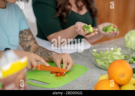 Les mains de deux femmes cuisant la salade de légumes. Banque D'Images