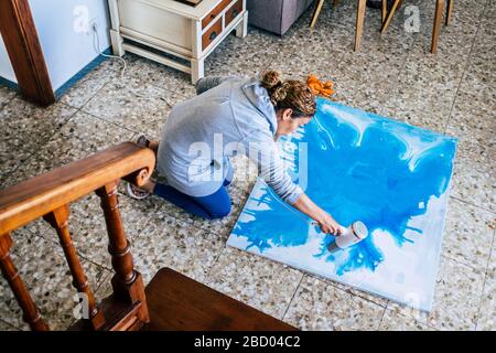 des œuvres d'art à la maison et des gens qui font de l'art peint à l'étage de la maison - caucasienne femme et papier bleu mur - activité artistique en quarantaine plus vie Banque D'Images