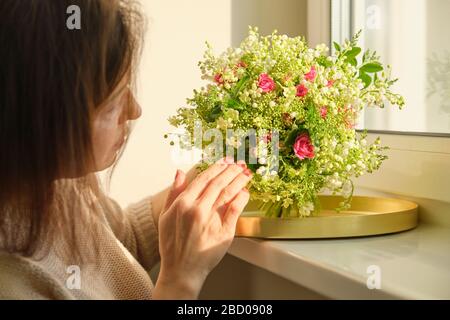 Bouquet de lilas des roses de la vallée des plantes vertes dans la main de la femme Banque D'Images