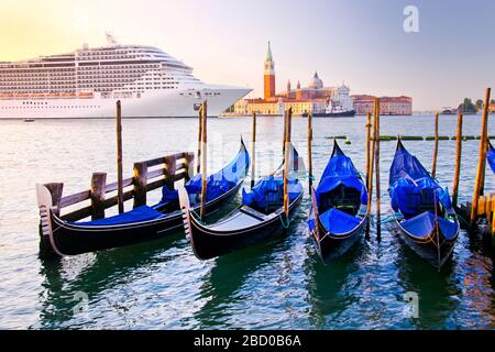 Venise avec des gondoles sur le Grand Canal contre l'église San Giorgio Maggiore en Italie avec un grand bateau de croisière dans la belle lumière du matin d'été lever de soleil Banque D'Images