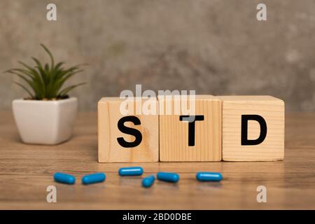 Foyer sélectif de blocs avec des lettres std, des pilules et des plantes sur table en bois sur fond gris Banque D'Images