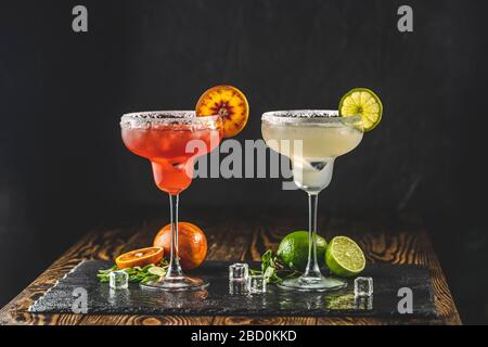 Mélange de cocktail de margarita et de margarita orange dans des verres à bords salés. Fond en bois sombre. Concentrez-vous sur la tranche d'agrumes. SHA Banque D'Images