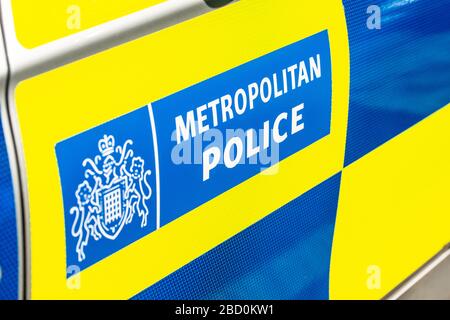 Vue inclinée du panneau de police métropolitaine sur la porte latérale de la voiture de patrouille à réponse rapide, recouverte de bleu et de jaune haute visibilité. Banque D'Images