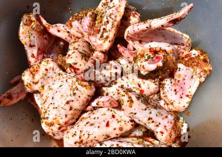 Ailes de poulet de la gamme libre aromatisées aux flocons de piment poivre noir persil séché huile de colza et paprika chaude tendre saine entrée à griller Banque D'Images