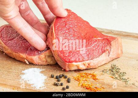 L'homme touche des steaks de boeuf pour barbecue. Viande fraîche prête à préparer un dîner. Banque D'Images