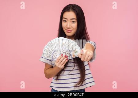 Vous pouvez devenir riche! Portrait de belle fille avec des cheveux de brunette pointant vers l'appareil photo et tenant des dollars, encourageant à gagner de l'argent, le choix de loterie Banque D'Images