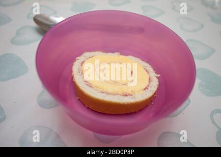 Gros plan d'un rouleau artique dans un bol en plastique rose sur la table de cuisine Banque D'Images