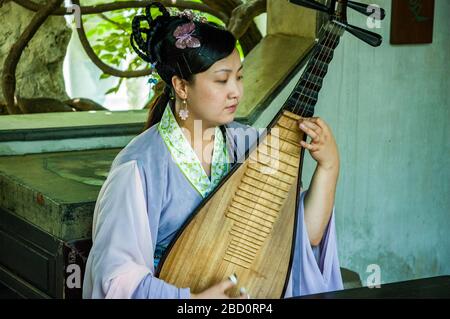 Musicien femelle joue un pipa, un instrument à cordes traditionnel chinois, dans les jardins de Suzhou persistante. Suzhou, Province de Jiangsu, Chine. Banque D'Images