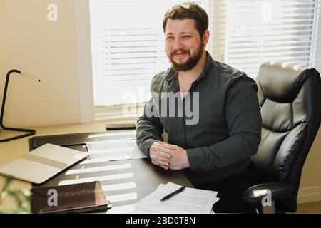 Manager assis au cabinet avec documents et ordinateur portable, tablette sur table. Banque D'Images