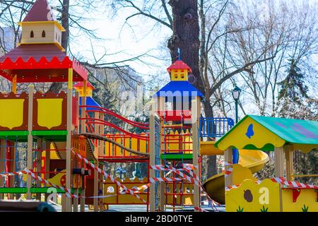 Aire de jeux pour enfants fermée et enveloppée dans un ruban de mise en garde pour la quarantaine mondiale du coronavirus.pas d'enfants sur les aires de jeux. Prévention du coronavirus Banque D'Images