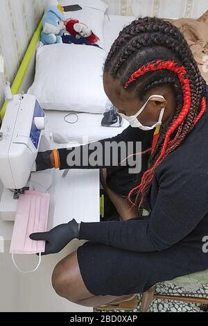 Quatre couturières de migrants, Justina, Rachel, Zainab et Rhoda du Nigeria et de la Côte d'Ivoire qui, avec Syll et bienheureux, tous les détenteurs de la protection internationale, le premier du Sénégal et le second du Nigeria, ont décidé de faire du bénévolat, De consacrer leurs compétences d'adaptation à la production de masques dans le matériel stérilisé TNT pour être distribué gratuitement dans la région de Naples. Pour coordonner les bénévoles, c'est LA moins coopérative sociale et L'ASSOCIATION ARTUR qui les suit dans leur voie d'insertion et d'inclusion sociale et professionnelle. ph. roberta basile kontrolab Banque D'Images