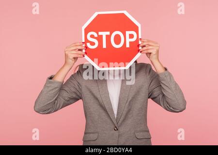 Portrait d'une personne d'affaires inconnue dans une veste de costume couvrant le visage avec le symbole Stop, une femme anonyme tenant l'arrêt du panneau rouge de signalisation, avertissement de danger, r Banque D'Images