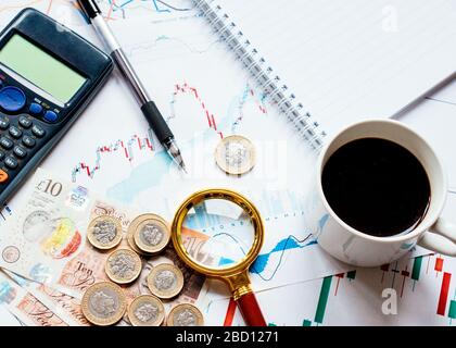 Une calculatrice d'argent (livres, livres sterling), une casquette de café, une loupe et différents tableaux d'argent sur la table. Vue du haut. Banque D'Images