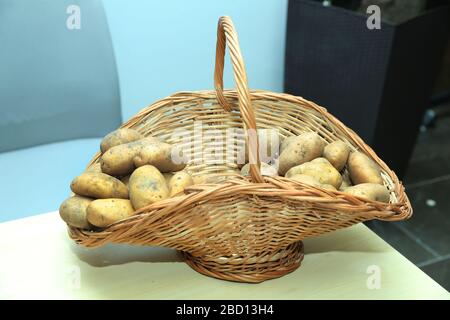 Pommes de terre frites dans un bol en bois . Le panier n'est pas bouilli dans les pommes de terre . Pommes de terre peau lavée non cuite sur la table en bois à pois polka millésime Banque D'Images