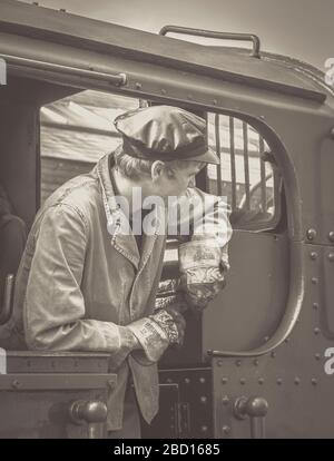 Gros plan noir et blanc du conducteur de train à vapeur dans la cabine de locomotive à vapeur ancienne, Severn Valley Railway Heritage Line, Royaume-Uni. Banque D'Images