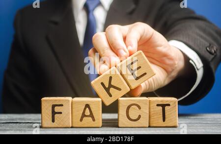 Un homme met des blocs de bois avec les mots fait et faux. Concept de nouvelles et de fausses informations. Pression jaune. Banque D'Images