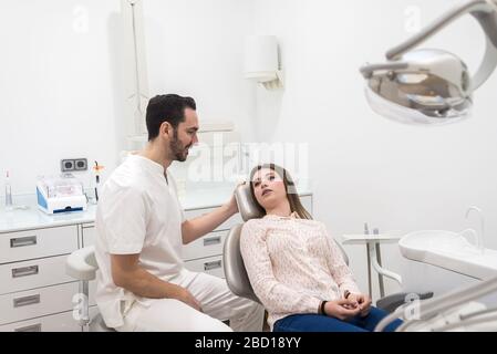 Dentiste barbu mâle expliquant la procédure à une patiente Banque D'Images