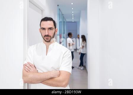 Portrait d'un médecin barbu debout avec les bras croisés dans le couloir Banque D'Images