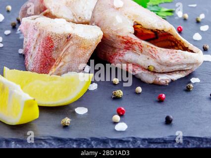 Filet de mérou rouge aux épices, citron, basilic sur fond de panneaux sombres Banque D'Images