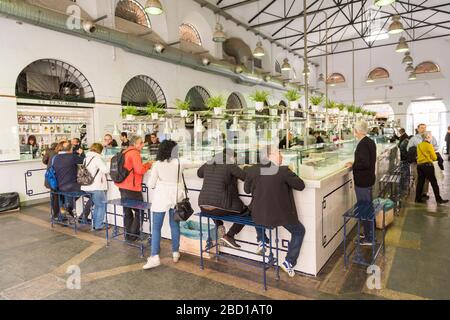 Les clients qui ont l'air dans un restaurant du Mercado de Triana, le marché intérieur de la nourriture à Triana Séville Espagne Banque D'Images