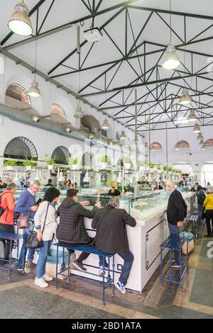 Les clients qui ont l'air dans un restaurant du Mercado de Triana, le marché intérieur de la nourriture à Triana Séville Espagne Banque D'Images