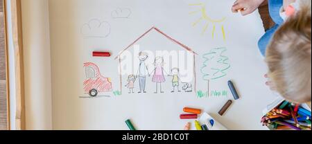 Les enfants dessinant une famille heureuse à l'intérieur de la maison Banque D'Images