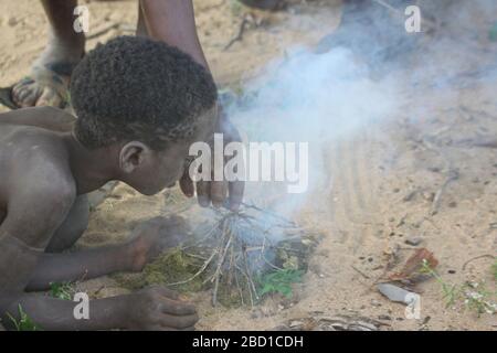 Afrique, Tanzanie, Lac Eyasi, jeune homme Hadza enfant allume un feu. Hadza, ou Hadzabe, est un groupe ethnique autochtone du centre-nord de la Tanzanie, le libin Banque D'Images