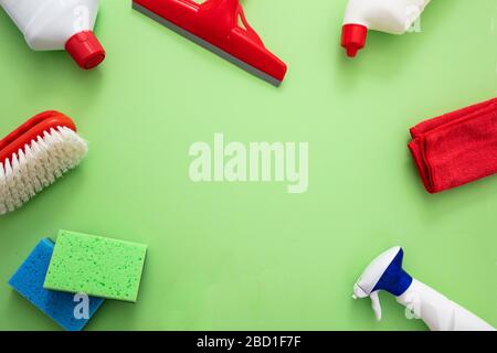 Nettoyage du ménage. Produits de nettoyage à plat, bouteilles de détergent chimique et équipement sur fond vert, vue du dessus, espace de copie Banque D'Images