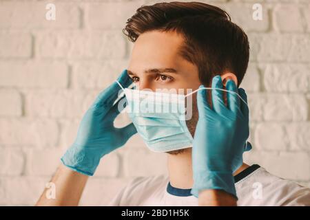 Un jeune chirurgien confiant dans des gants de protection en latex portant un masque médical sur le visage. Homme professionnel médique dans les gants médicaux mis sur protection fac Banque D'Images