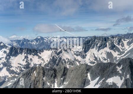 Aérien, à partir d'un planeur, d'un autre planeur survolant la crête de roche sombre à Mt. Barth range, tourné dans une lumière de printemps vive de l'ouest, Otago, South Island, N Banque D'Images