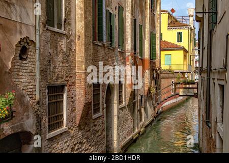 Un canal étroit avec un petit pont en bois menant à poste Vecie un restaurant italien près du marché aux poissons du Rialto à Venise, Italie Banque D'Images