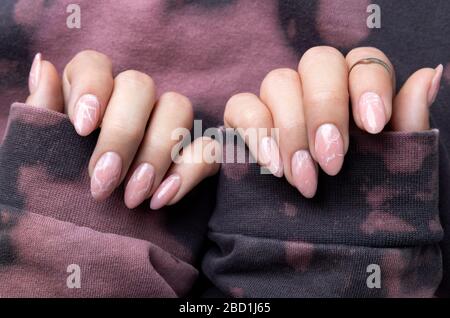 Les mains des femmes sont parfaitement soignés dans un sweat à capuche rose tendance Banque D'Images