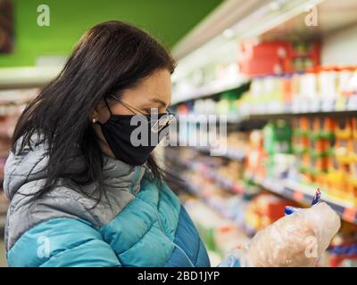 femme avec masque protecteur sur son visage achète dans un centre commercial pendant une pandémie de coronavir Banque D'Images