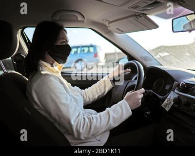 femme avec masque de protection sur son visage conduisant la voiture pendant une pandémie de coronavir Banque D'Images