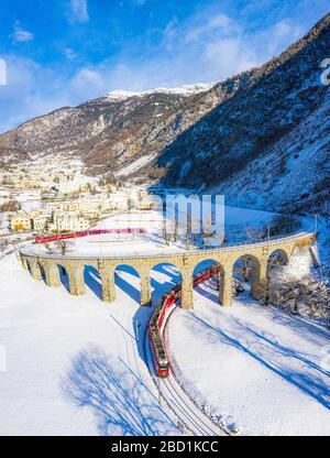 Bernina Express passe sous le viaduc hélicoïdal (spirale) de Brusio, site classé au patrimoine mondial de l'UNESCO, Valposchiavo, Canton de Graubunden, Suisse Banque D'Images