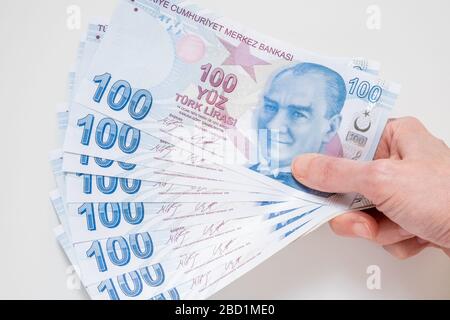 Main féminine tenant un groupe de 100 billets de Lira (TRY) turcs isolés sur fond blanc. Banque D'Images