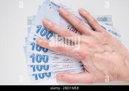 Main féminine sur un groupe de 100 billets de Lira (TRY) turcs isolés sur fond blanc. Banque D'Images