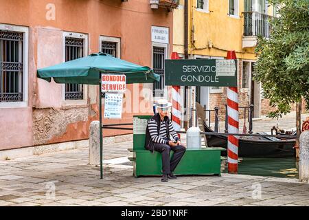 Un gondolier assis sur une boîte verte attendant que les touristes prennent une télécabine à Campo Santo Stefano, Venise, Italie Banque D'Images