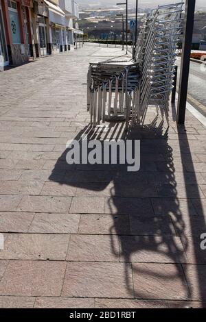 Meubles de terrasse de restaurant empilés le long du front de mer à Playa San Juan, Tenerife, îles Canaries, Espagne Banque D'Images