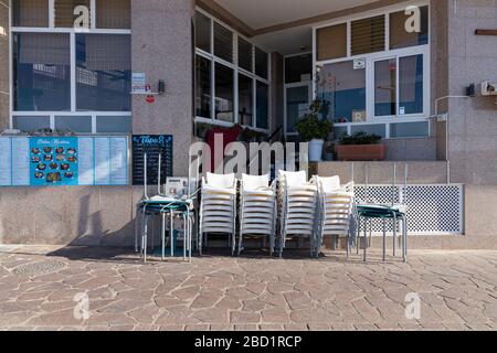 Meubles de terrasse de restaurant empilés le long du front de mer à Playa San Juan, Tenerife, îles Canaries, Espagne Banque D'Images