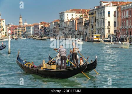 Deux gondoliers se parlent les uns avec les autres alors qu'ils dirigent leurs gondoles transportant des touristes sur le Grand Canal, Venise, Italie Banque D'Images